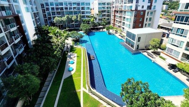 Un hotel moderno con una piscina central rodeada de abundante vegetación y múltiples pisos de balcones.