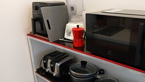 Una kitchenette equipada con tostadora, licuadora, microondas y cafetera.