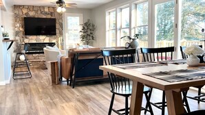 A spacious kitchen with a stone backsplash, a dining area with a large table and chairs, and a TV mounted on the wall. - Get Cozee Pequot Lakes, Lakefront on Mayo/Sibley (Pequot Lakes)