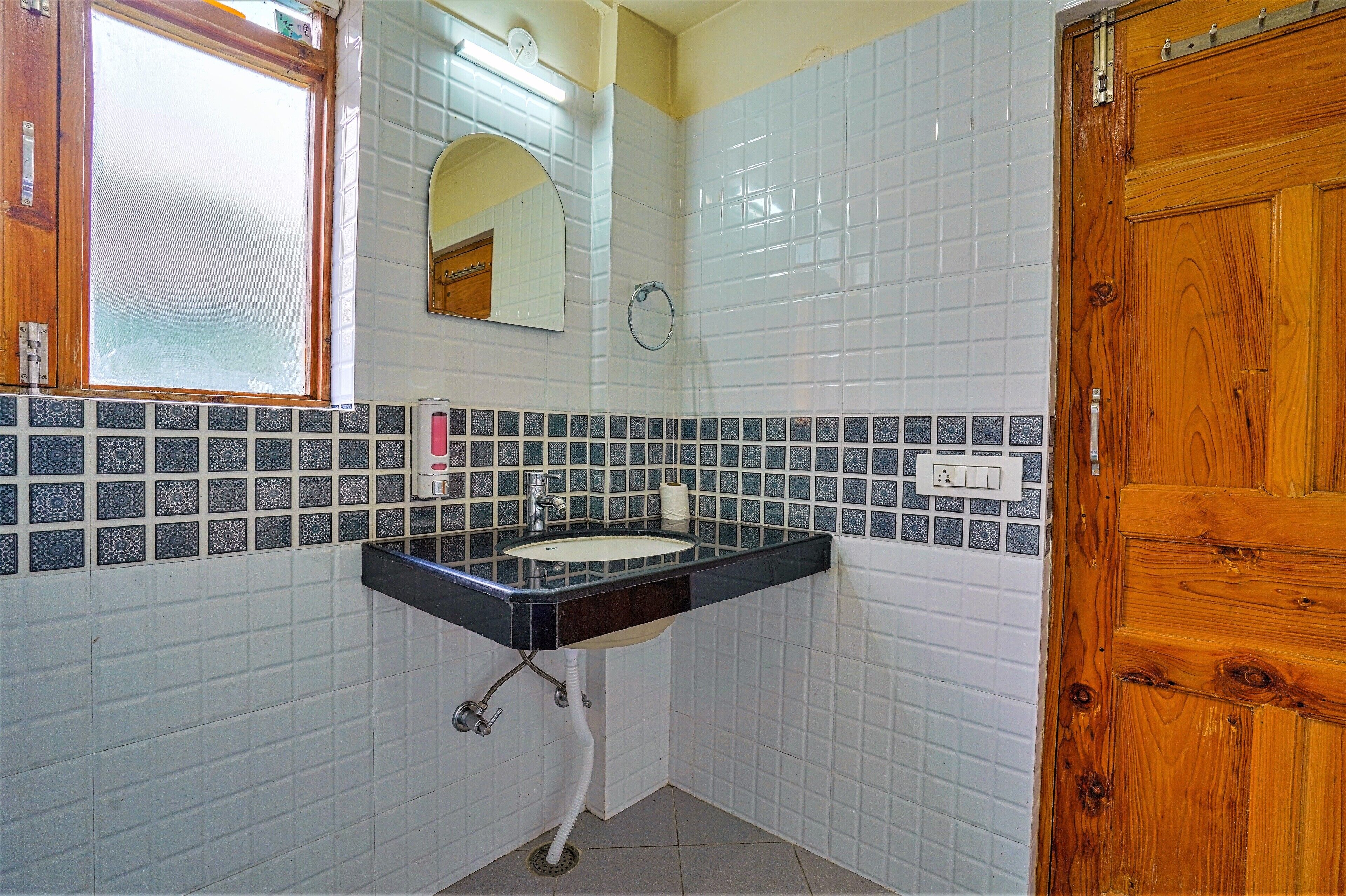 Ein Badezimmer mit Waschbecken, Spiegel und Holztür.