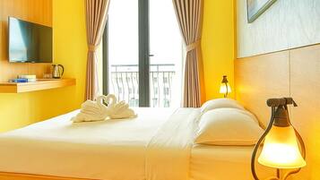 Quarto de hotel com cama, televisão, ar-condicionado fixado na parede e um quadro.