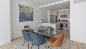 Eine moderne Küche mit Edelstahlgeräten, einem Glastisch und blau gemusterten Stühlen.