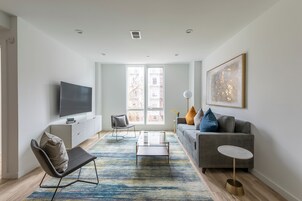 A modern living room with a sofa, a coffee table, a TV, and a large window.