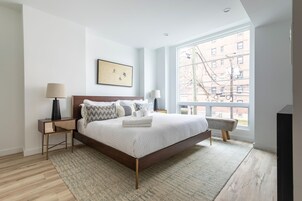 Un dormitorio moderno con una cama grande, vistas a la ciudad y un diseño minimalista.