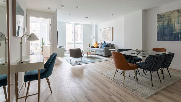 A modern living room with a dining area, featuring a sofa, coffee table, and a dining table with chairs.