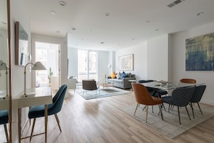 A modern living room with a dining area, featuring a sofa, coffee table, and a dining table with chairs.