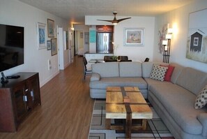 A modern living room with a sectional sofa, a wooden coffee table, and a TV on a cabinet.