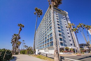 A high-rise hotel with a modern design, featuring a prominent glass facade and multiple balconies.