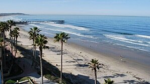 A beach with palm trees, a pier, and a clear sky.