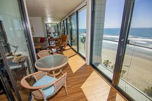 Un balcone con vista sulla spiaggia, arredato con sedie in vimini e un tavolo.