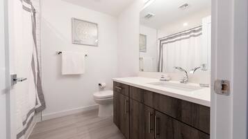 Une salle de bain moderne équipée de toilettes, d’un lavabo et d’une douche.
