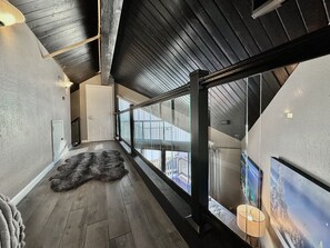 Stylish corridor with a high ceiling, glass railing, and framed artwork.