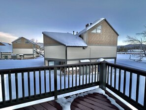 Cozy home with a gabled roof and chimney, surrounded by a deck with a railing.