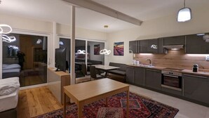Une cuisine moderne avec des meubles de couleur sombre, un plan de travail en bois et un four encastré.