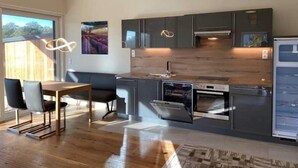 Une cuisine moderne avec des meubles de couleur sombre, un plan de travail en bois et un four encastré.
