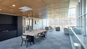 A modern conference room with a long table, chairs, and a kitchen area. - Modern 3 BR Loft -shared Deck - gym - Mins to NYC (Hoboken)