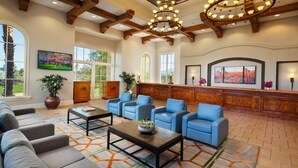 A spacious lobby with a reception desk, blue seating area, large windows, and a chandelier. - Marriott's Shadow Ridge II (Palm Desert)