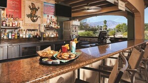 A bar area with a granite countertop, bar stools, and a view of mountains. - Marriott's Shadow Ridge II (Palm Desert)