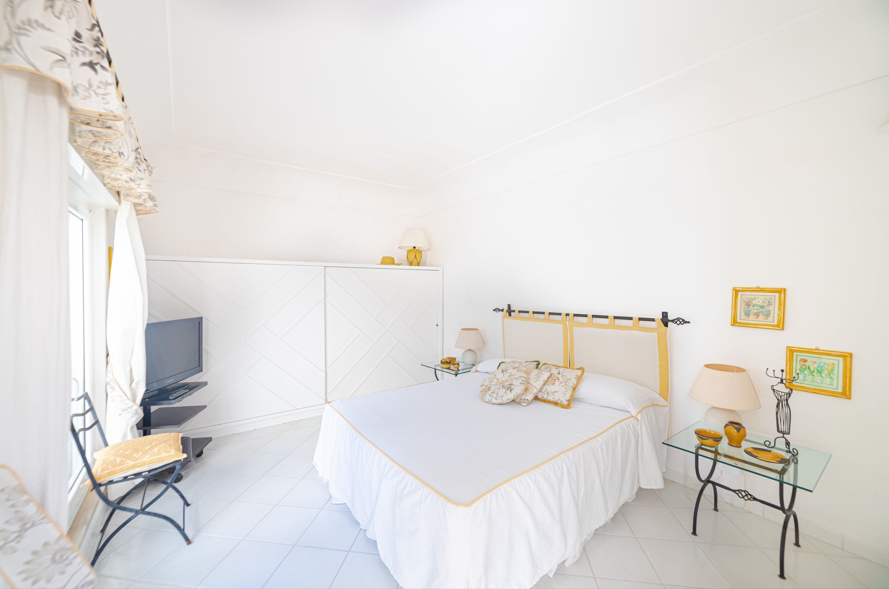 Un dormitorio con cama, escritorio, silla, televisor y lámpara.