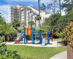 Children can play on the slides and climbing frames in this well-maintained playground surrounded by grass and trees.