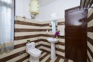 A bathroom with striped tile walls, a toilet, a sink, and a shower.