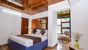 Ein Schlafzimmer mit einem großen Bett, Holzbalkendecke und Blick ins Freie durch ein Fenster.