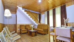 Ein Wohnzimmer mit Holzboden, einer Treppe, zwei Sofas, einem Couchtisch und einem für vier Personen gedeckten Esstisch.