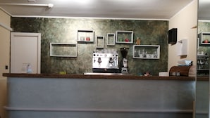 A kitchen with a coffee machine, shelves with cups, and a counter. - BRENNERO  (Rimini)
