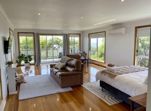Une chambre spacieuse avec un grand lit, un canapé en cuir marron et un coin repas comprenant une table et des chaises.