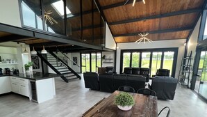 Una cocina moderna y espaciosa con una isla central, un comedor con mesa de madera y un salón con sofás de cuero negro.