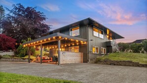 Une maison moderne à deux étages dotée d’un patio couvert.