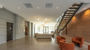 Um hall amplo com design moderno, apresentando uma grande área de estar, uma escadaria e vista para o exterior.