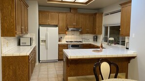 A kitchen with wooden cabinets, a white refrigerator, a stove, and a microwave. - Beautiful peaceful desirable home in Madera Rancho (Madera)