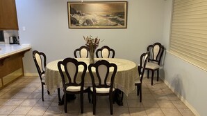 A dining area with a round table, six chairs, a vase with dried flowers, and a painting on the wall. - Beautiful peaceful desirable home in Madera Rancho (Madera)