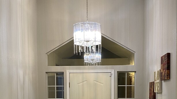 A hallway with a chandelier, a door, a bench, a fish tank, and a rug. - Beautiful peaceful desirable home in Madera Rancho (Madera)