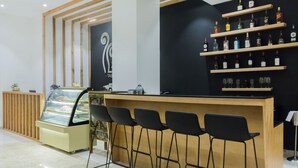 Un área de bar moderna con mostrador, taburetes negros y estantes llenos de botellas de licores.