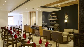 Un restaurante con mesas y sillas de madera, una zona de bar y un área de estar con sofás.