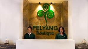 Una mesa de recepción con un cartel que dice 'PELYANG Boutique' y dos empleados de pie detrás.