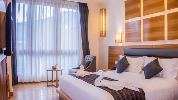 Una habitación de hotel con una cama grande, una silla, una mesita y un televisor.