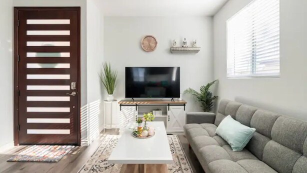 Ein modernes Wohnzimmer mit Flachbildfernseher, einer Couch, einem Couchtisch und einem dekorativen Regal.