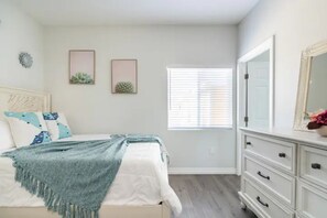 A bedroom with a bed, a dresser, and a window with blinds. - Modern Home Near Disneyland, Beaches, and Little Saigon (Midway City)
