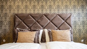 A bed with a tufted headboard, multiple pillows, and a patterned wallpaper background. - FerBeautiful apartment close to the Netherlands (Ahaus)