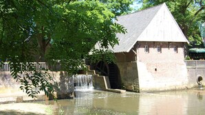 A historic building with a water feature, a stone wall, and a tree in the foreground. - FerBeautiful apartment close to the Netherlands (Ahaus)