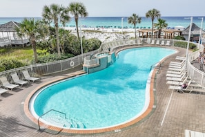 A curved pool with a view of the beach and ocean.