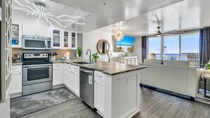 A modern kitchen with white cabinetry, stainless steel appliances, and a large island.