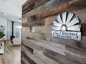 Una pared rústica con un letrero de metal que dice 'Family & Friends Gather Here'.