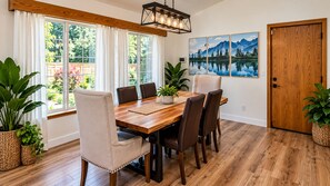 A dining area with a wooden table, chairs, potted plants, and a painting of mountains. - Oasis Riverfront House - Gazebo overlooks the River, 5 miles to Sequoia SNP gate (Three Rivers)