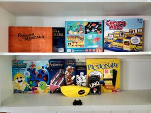 Un estante con varios juegos de mesa, incluyendo 'Chess Who?' y 'Pictionary'.