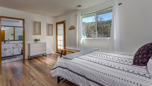 A bedroom with a large bed, a dresser, a mirror, and a window with a view of trees. - Oasis Riverfront House - Gazebo overlooks the River, 5 miles to Sequoia SNP gate (Three Rivers)