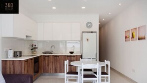 Una cocina moderna con armarios blancos, encimera de madera y comedor con mesa y sillas blancas.